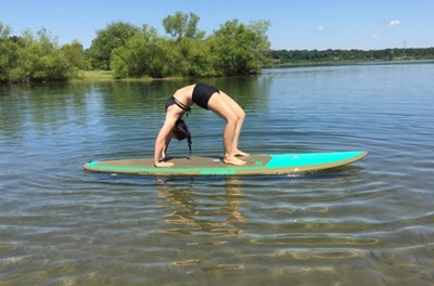 Rachelle doing chakrasana yoga pose on a surfboard